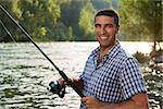 mid adult fisherman on holidays on river, relaxing and fishing trouts