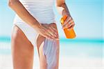 Closeup on young woman applying sun block creme on beach