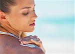 Portrait of young woman applying sun screen creme