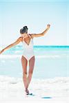 Full length portrait of young woman walking on sea coast