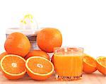 Glass of orange juice, peel, oranges and juicer.
