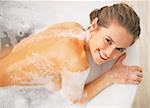 Smiling young woman laying in bathtub