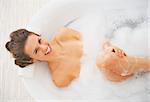 Portrait of smiling young woman laying in bathtub