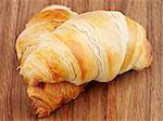 Two Freshly Baked Croissants on Wooden background