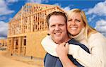 Happy Excited Couple in Front of Their New Home Construction Framing Site.