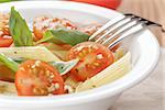 simple italian pasta penne with tomatoes and basil, on table