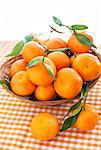 Fresh tangerines with leaves in a  basket on the table