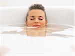 Young woman laying under water in bathtub