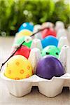 Colorful painted Easter eggs in a carton on the green background, selective focus
