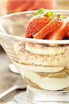 Italian dessert tiramisu decorated with strawberries in a glass beaker