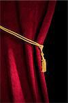 Red velvet curtain with tassel. Close up black isolated curtain