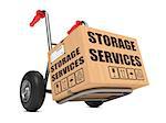 Cardboard Box with Storage Services Slogan on Hand Truck White Background.