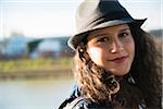 Close-up portrait of teenage girl outdoors, wearing fedora, smiling and looking at camera, Germany