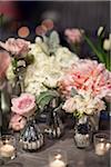 Close-up of vases with roses and peonies on table with candlelit votive holders at reception, Canada