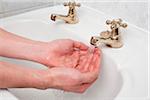 Close-up of man washing hands in bathroom sink, studio shot