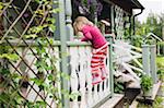 3 year old girl in rubber boots climbing on veranda, Sweden