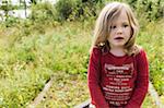 Close-up portrait of 3 year old girl in red shirt sitting in field, Sweden