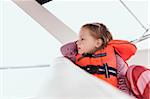 Close-up of 3 year old girl in orange life jacket on a motorboat, Sweden