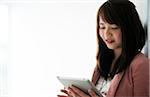 Close-up portrait of young woman looking down at tablet computer and smiling, Germany