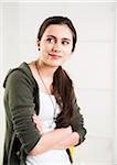 Portrait of teenage girl with arms crossed, looking to the side and smiling, studio shot on white background