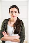 Portrait of teenage girl with arms crossed, looking at camera and smiling, studio shot on white background