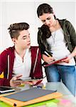 Teenage boy and teenage girl working together using tablet computer and file folders, studio shot