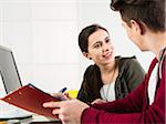 Teenage boy and teenage girl working on project using desktop computer and file folders, studio shot