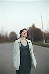 Attractive woman with retro coiffure walking street wearing white coat.