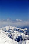 Winter snowy mountains and blue sky with clouds. Caucasus Mountains, Georgia, view from ski resort Gudauri.