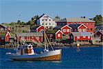 Red fishing rorbu huts and fishing boat in town of Reine on Lofoten islands