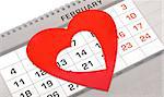 Red heart shape marker on calendar page showing February 14 Valentine's day