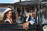 Pair of 1920s vintage gangsters waiting inside an antique car