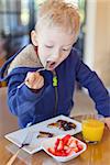 cheerful little boy eating breakfast