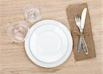 Empty plate, wine glasses and silverware set on wooden table
