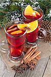 Christmas mulled wine with spices and snowy fir tree on wooden table