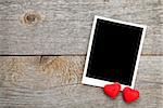 Photo frame and small red candy heart on wooden background