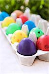 Colorful painted Easter eggs in a carton on the green background