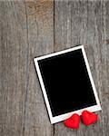 Photo frame and small red candy hearts on wooden background