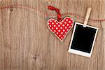 Blank instant photo and red heart hanging. On wooden background with copy space