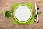 Fork with knife, blank plates, empty cup and napkin. On wooden table background