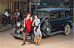 Group of 1920s gangsters near old car with guns