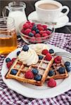 Breakfast with belgian waffles decorated with whipped cream and fresh berries