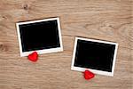 Two photo frames and small red candy hearts on wooden background