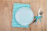 Fork with knife, blank plates and napkin. On wooden table background