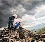 Tourist sitting on the rocks under cloudy sky