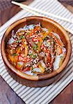Rice noodles with meat and vegetables in wooden bowl