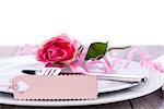 Valentines table setting with an ornamental blank pink gift tag and romantic rose to celebrate the holiday with a loved one
