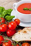 tasty fresh tomato soup basil and bread on wooden background