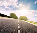 Asphalt road in green meadow. Belarus.  Sunset