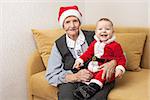 Christmas funny small baby in Santa Claus clothes with his grandmother